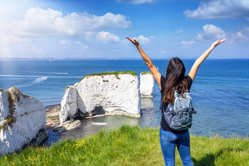 A happy tourist woman enjoys the view of the Old Harry Rocks, Jurrasic Coast, Dorset, England,...