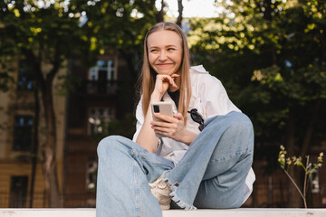 People emotions, lifestyle leisure and beauty concept. Dreamy and excited happy young blonde woman using mobile phone, smiling and looking thoughtful at side, have idea, search solutions, thinking.