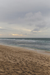 Ocean waves break on empty sand beach during cloudy gloomy day