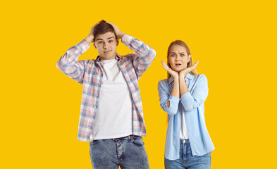 Portrait of two shocked people. Man and woman bewildered by unexpected situation. Young couple isolated on yellow background looking at something with scared surprised confused nervous face expression