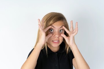 beautiful teen girl wearing black dress over white studio background keeping eyes opened to find a success opportunity.