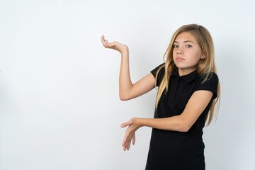 beautiful teen girl wearing black dress over white studio background pointing aside with both hands showing something strange and saying: I don't know what is this. Advertisement concept.