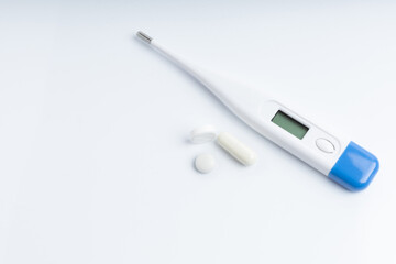 The thermometer and capsule tablets on a white background with space for text