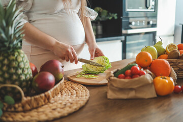 Pregnant woman making salad in her kitchen, healthcare