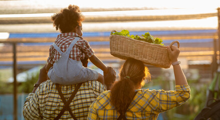 Happy farmer parents dad father with daughter child on piggyback walking fun with mum in garden...
