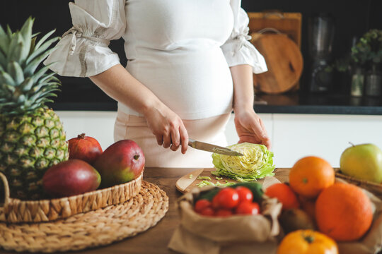 Pregnant woman making salad in her kitchen, healthcare