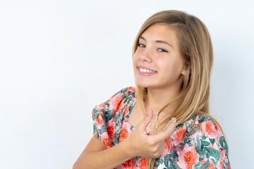 beautiful caucasian teen girl wearing flowered blouse over white wall holding an invisible aligner...