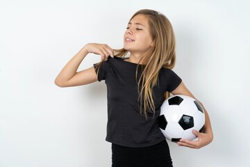 beautiful caucasian teen girl wearing sportswear holding a football ball over white wall stressed, anxious, tired and frustrated, pulling shirt neck, looking frustrated with problem