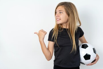 beautiful caucasian teen girl wearing sportswear  over white wall points away and gives advice demonstrates advertisement