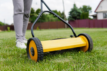 Woman lawn mowing with a manual push lawn mower