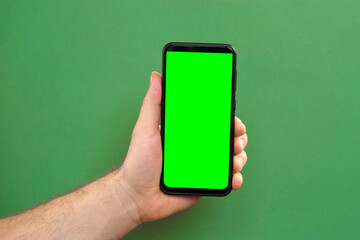 Young man hand use smartphone with green screen on green background. Gestures pack. Male hand touching, clicking, tapping swiping on black phone chroma key display. Close up Device. Modern Technology