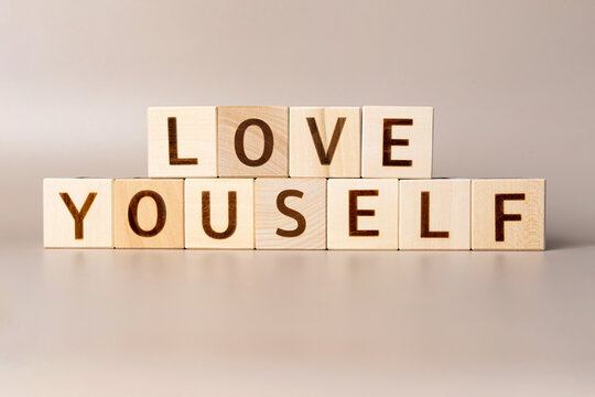 The word LOVE YOURSELF on wooden cubes on a beige neutral studio background. Copy Space. Written. Text words matter. Human mental health. Skincare Body care. Be You Self Esteem Confidence Encourage