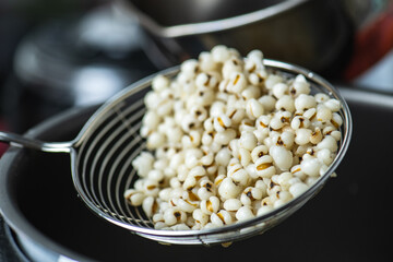 Hot Boiled Job’s Tears millet seed from boiler. White boiled Job’s Tears is highly nutritious cereal healthy fresh organic in salad dish.