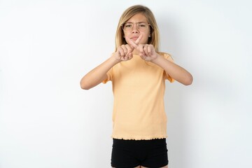 beautiful caucasian teen girl wearing orange T-shirt over white wall has rejection angry expression...