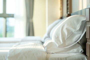 Soft pillows and white towel on clean white bed. Pillows bed with bedding sheets in bedroom. Bed...