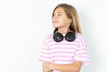 Fototapeta premium Self confident serious calm beautiful caucasian teen girl wearing striped T-shirt over white wall stands with arms folded. Shows professional vibe stands in assertive pose.