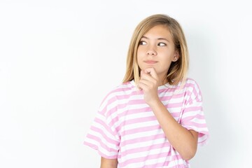 Shocked embarrassed beautiful caucasian teen girl wearing striped T-shirt over white wall keeps mouth widely opened. Hears unbelievable novelty stares in stupor