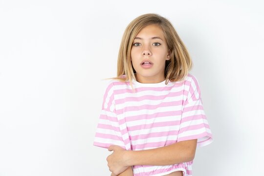 Charming thoughtful beautiful caucasian teen girl wearing striped T-shirt over white wall stands with arms folded concentrated somewhere with pensive expression thinks what to do