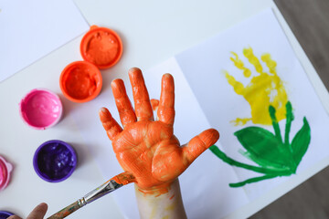 Children's art workshop, the child makes a handprint with paints