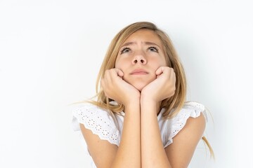 Fototapeta premium Portrait of sad beautiful caucasian teen girl wearing white T-shirt over white wall hands face look empty space