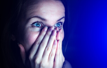 Woman is watching something scary. Close up scared girl face.