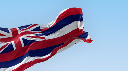 The flag of Hawaii waving in the wind on a clear day