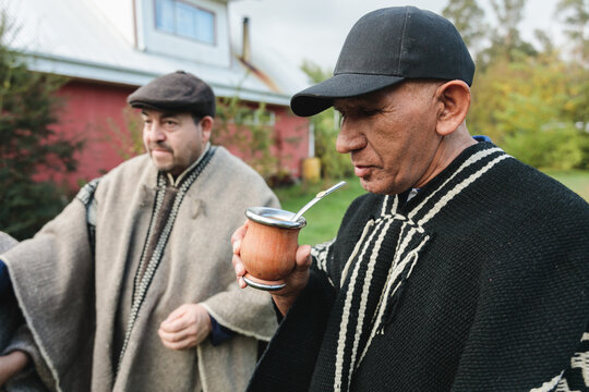 Senior friends in woolen ponchos sharing hot tea in park