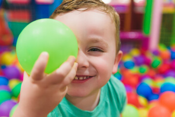 Fototapeta na wymiar Child on the playground with colored plastic balls