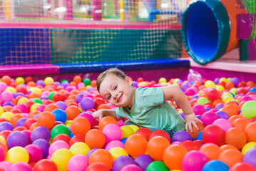 Fototapeta na wymiar Portrait of three funny little kids playing in ball pit and enjoying time in childrens entertainment and play area, copy space