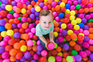 Fototapeta na wymiar Happy child playing and having fun in kindergarten with colorful balls
