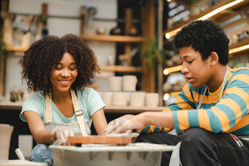 Creative afro American young woman artist molding clay form by hand finger on pottery wheel, handcraft workshop in ceramic creation studio, making a pot material in hobby and leisure with pleasure