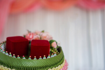 A red wedding ring box placed on a tray made of banana leaves is a Thai wedding decoration.