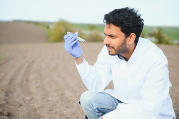 Soil Testing. Indian Agronomy Specialist taking soil sample for fertility analysis. Hands in gloves close up. Environmental protection, organic soil certification, field work, research