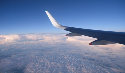 Airplane in flight above cloudy sky . Aerial top view from air wing plane window