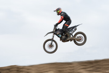 Fototapeta na wymiar Unrecognized athlete riding a sports motorbike jumping on the air on a motocross race. Fast speed extreme sport.