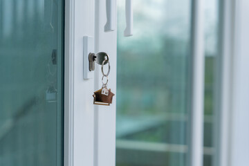 Landlord key for unlocking house is plugged into the door. Second hand house for rent and sale. keychain is blowing in the wind. mortgage for new home, buy, sell, renovate, investment, owner, estate