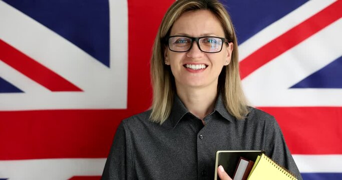 Young smiling woman in glasses standing on background of UK flag 4k movie. English language learning concept