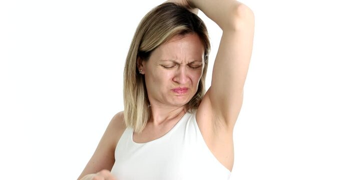 Woman sniffing armpit and closing nose from unpleasant smell 4k movie slow motion. Problems with excessive sweating in women concept