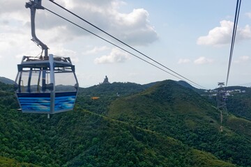 Scenic view of a gondola of Ngong Ping Cable Car (Skyrail) gliding over lush forests on the...