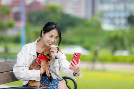 Woman take selfie on mobile phone with her dog at park