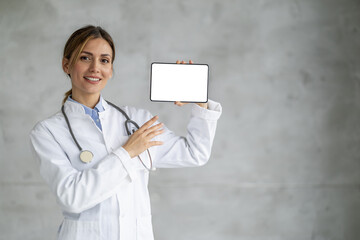 Portrait of female doctor holding digital tablet and showing free space