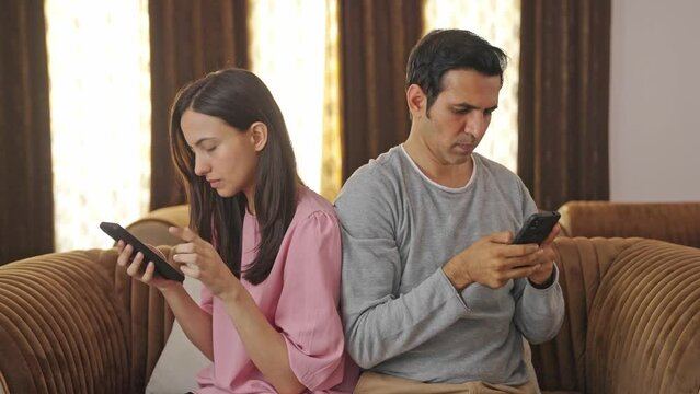 Indian husband and wife busy in their mobile phones