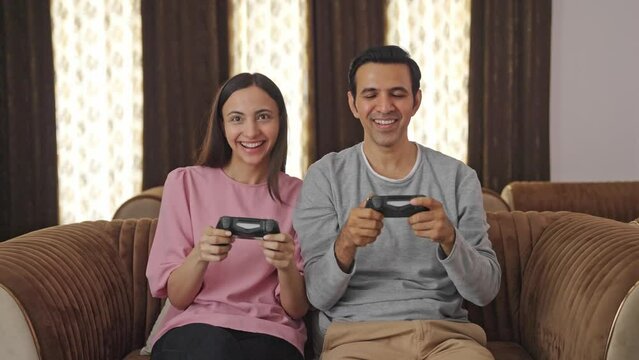 Happy Indian couple playing video games