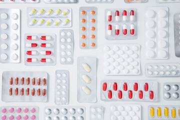 Various tablets and capsules in blisters on white background. Concept of healthcare and medicine. Top view
