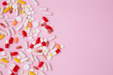 Various colorful medication tablets and capsules on pink background. Concept of healthcare and...