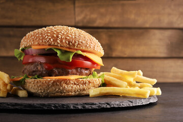 fresh burger burger made of bun, onions, tomato, ketchup, mayonnaise, cheese, lettuce, meat patty, beef, fries on a black table and black plate on a rustic wooden background