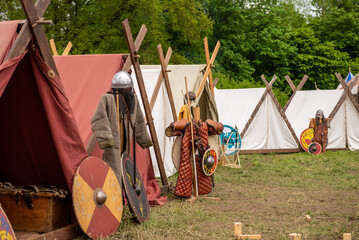 Medieval armor parts and weapons stand outside tents during a medieval festival