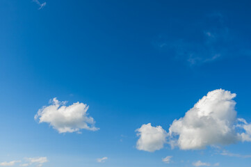 Naklejka na ściany i meble Fluffy white clouds in the blue sky on a sunny day.