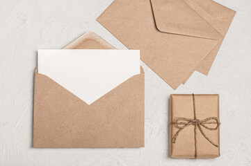 Invitation or greeting card mockup, empty blank, craft envelopes and craft gift box on light background.