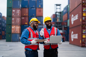 Two African engineers Supervising loading containers from cargo ships. logistics yard business...